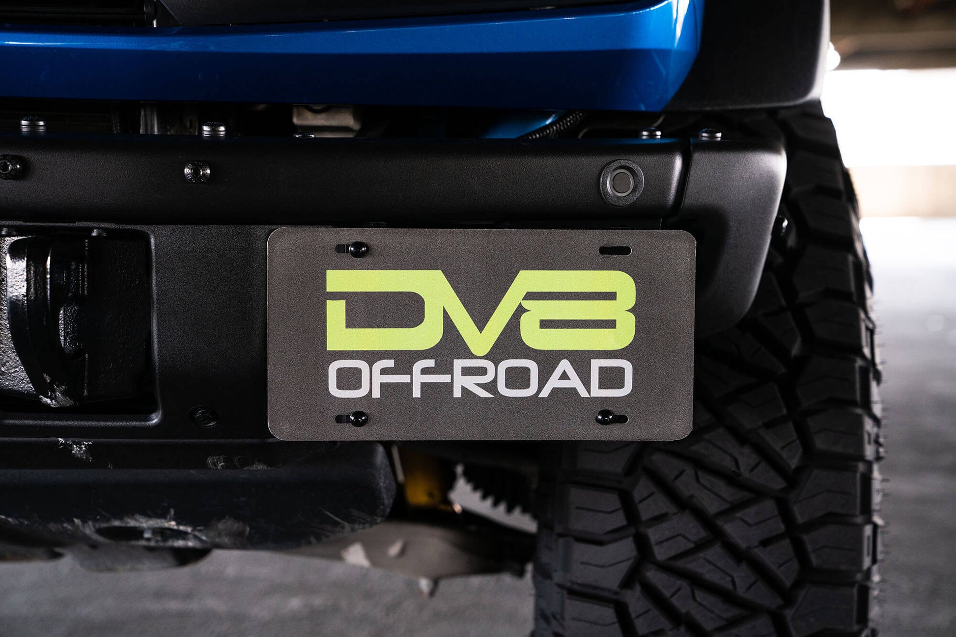Front license plate relocation bracket places plate to the side of the bumper. by DV8 Offroad