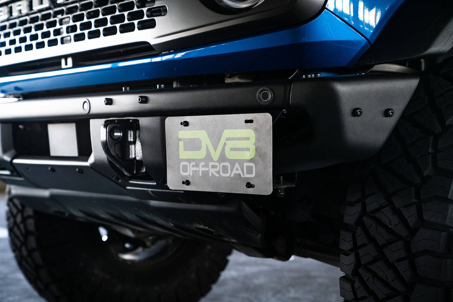 Front license plate relocation bracket places plate to the side of the bumper. by DV8 Offroad