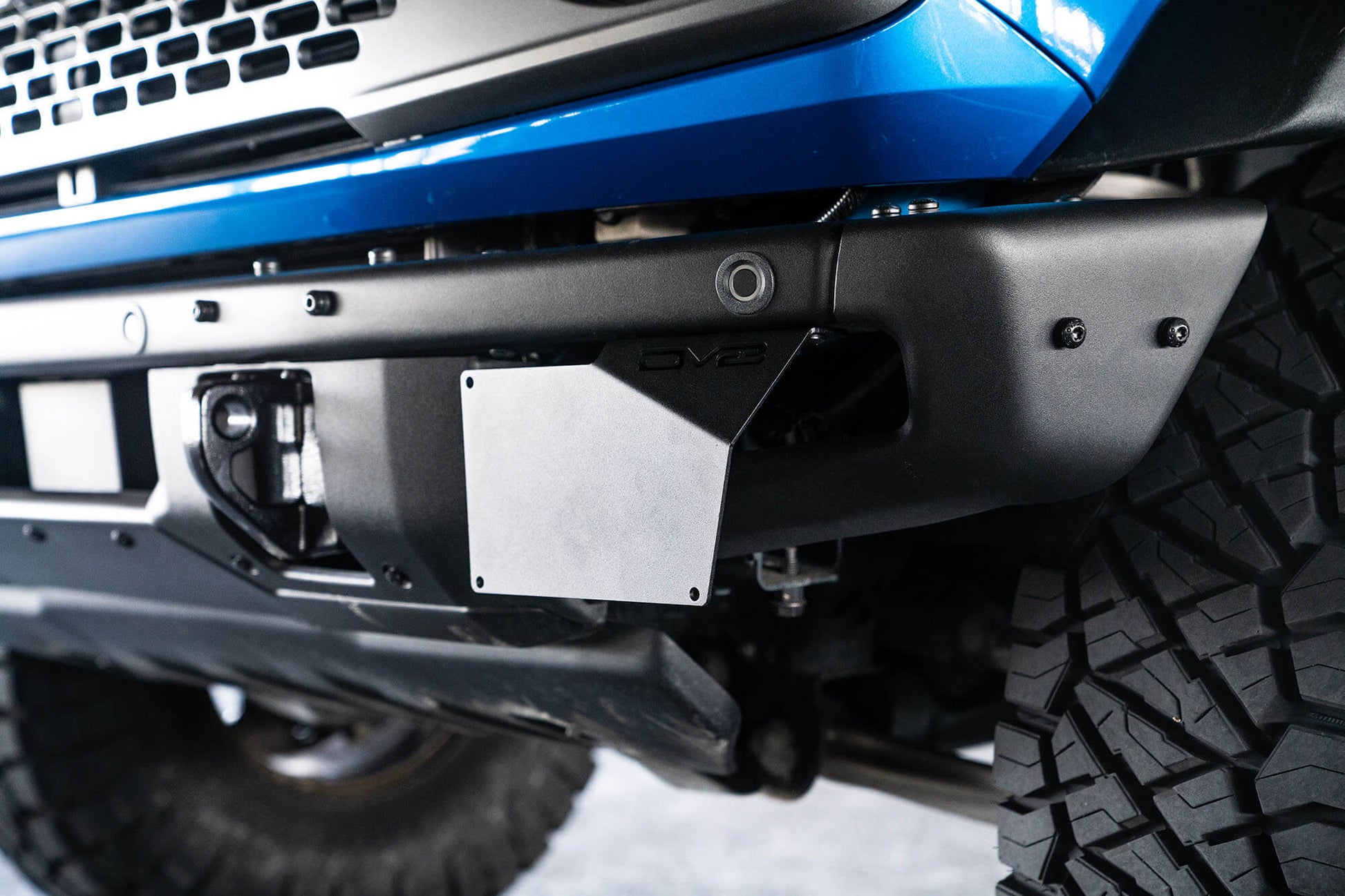 Front license plate relocation bracket places plate to the side of the bumper. by DV8 Offroad